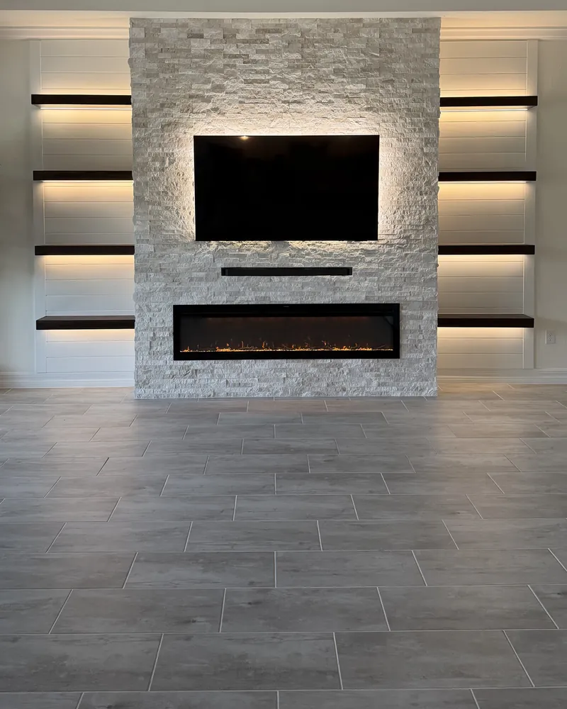 After: stacked stone, a backlit TV and a linear fireplace with lit shelves