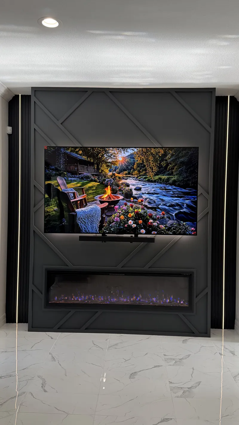 Graphite panel wall with raised diagonal trim, a backlit TV, a linear fireplace and black slats with vertical light lines